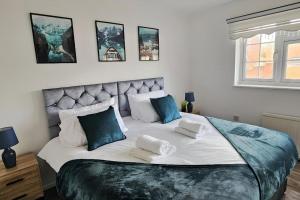 a bedroom with a large bed with blue pillows at 4 Bedroom Spacious Entire House Sleeps 6 in Great Parndon
