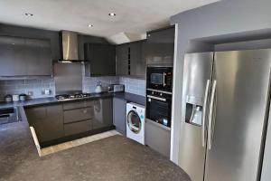 a kitchen with a stainless steel refrigerator and a dishwasher at 4 Bedroom Spacious Entire House Sleeps 6 in Great Parndon