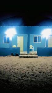 une maison bleue avec deux chaises devant elle dans l'établissement Jusula Beach Resort, à Sanyang
