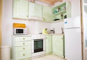a kitchen with green cabinets and a white refrigerator at Villa Mando in Super Paradise Beach
