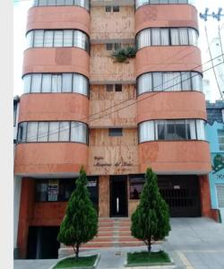 um edifício de tijolos alto com duas árvores em frente em habitación con baño en bucaramanga-cerca sena-uis em Bucaramanga