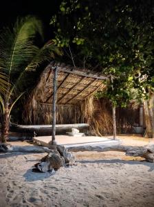 a straw hut on a beach with trees and sand at La Caracola Cartagena in Cartagena de Indias