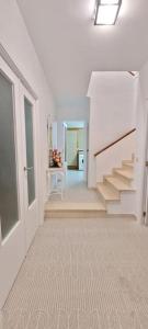 a white hallway with stairs and a table in a room at Casa la perla de sefarad in Lucena