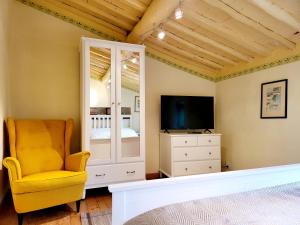 sala de estar con silla amarilla y TV en La casa degli artisti en Marliana