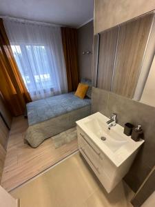 a bathroom with a sink and a bed with a window at Apartmán Úsvit in Banská Bystrica