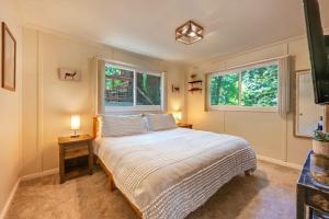 a bedroom with a large bed and two windows at River Otter Hot Tub BBQ Fire Pit Russian River Gem in Rio Nido