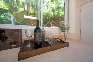 a bottle of wine on a tray with wine glasses at River Otter Hot Tub BBQ Fire Pit Russian River Gem in Rio Nido