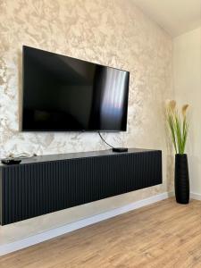 a flat screen tv on a wall with a vase at Apartman Star #2 in Vinkovci