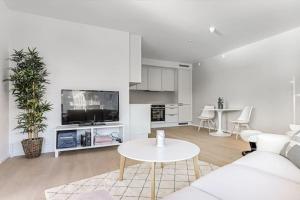 a white living room with a white couch and a table at New waterfront apartment - Oslo city centre in Oslo