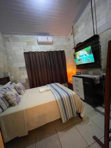 a bedroom with a bed and a flat screen tv at Casa de Pedra in Pirenópolis
