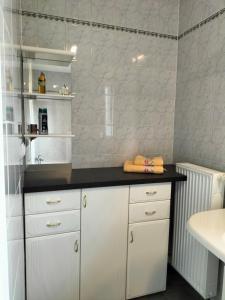 eine Küche mit weißen Schränken und einer schwarzen Arbeitsplatte in der Unterkunft Pension Rosenvilla in Sedlitz