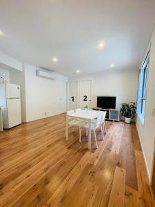 a living room with a white table and a kitchen at Modern Private Room 1,2 close to QEII & Grifith Uni in Brisbane