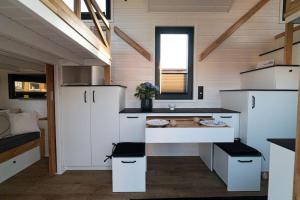 una cucina con armadi bianchi e un lavandino in camera di Tiny Silent House a Osówek