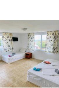a large room with two beds and a window at Krimski Guest House and Bungalows in Byala