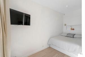 een witte slaapkamer met een flatscreen-tv aan de muur bij My little Port Grimaud in Grimaud