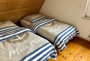 2 łóżka pojedyncze w niewielkim pokoju z drewnianą podłogą w obiekcie Ferienhaus Erdmann-Huus w mieście Esgrus