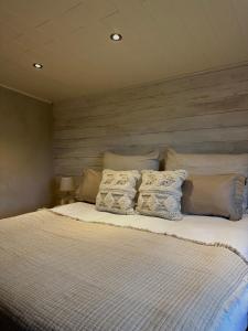 uma cama com almofadas num quarto em La Maisonnette em Theux