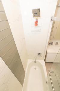 een witte badkamer met een bad en een wastafel bij Spacious 3-BR Luxury Suite near New York City in Union City