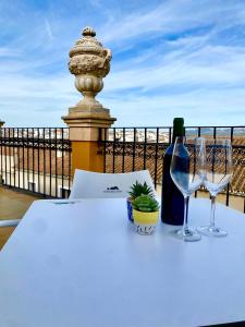 a table with a bottle of wine and two wine glasses at Apartamentos Abeto in Ronda