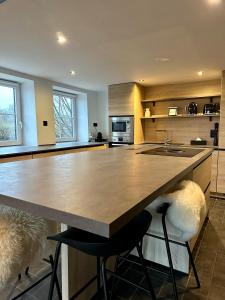 a kitchen with a large island with two bar stools at La Maisonnette in Theux +7 photos