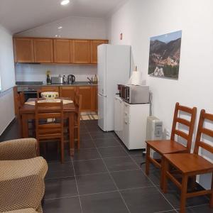 a kitchen with a white refrigerator and a table and chairs at Casas da Escola - "A Escola" - Meãs in Pampilhosa da Serra