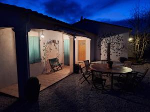 a patio with a table and chairs at night at Villa les terre rouges avec piscine Aude in Arques