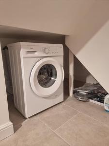 uma máquina de lavar e secar roupa num canto de um quarto em Entire Ground Floor Flat, Free Off-Street Parking and Large Garden em Londres