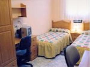 a hotel room with two beds and a desk and a chair at Hostal Vadama in Segovia