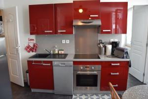 a kitchen with red cabinets and a stove top oven at T2 tout confort 1 chambre, proche hypercentre classé 2 étoiles in Le Mont-Dore
