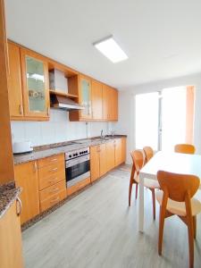 una cucina con mobili in legno, tavolo e sedie di Neboa a Viveiro