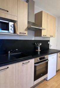 a kitchen with a sink and a microwave at Appartement vue sur mer in Plérin