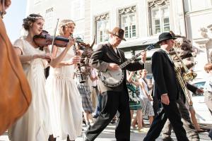 um grupo de pessoas tocando música na rua em Boutiquehotel am Dom em Salzburgo