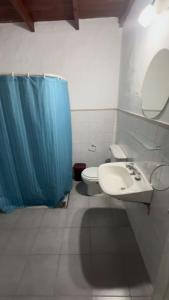 uma casa de banho com um lavatório, um WC e uma cortina de chuveiro azul. em A CAZON QUITADO em Saladillo