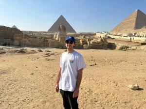 un hombre está parado frente a las pirámides en Sun light pyramids inn en El Cairo