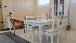 uma sala de jantar com uma mesa branca e cadeiras em Lugas Apartman em Villány