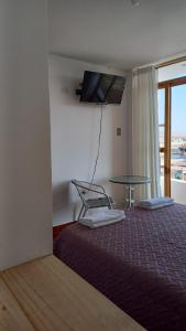 Zimmer mit einem Bett, einem Tisch und einem Fenster in der Unterkunft El Capricho II Paracas in Paracas