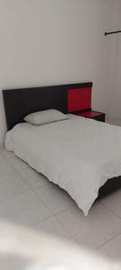 a bedroom with a white bed with a red headboard at HOSTAL CARACOLI - HUECO in Valledupar
