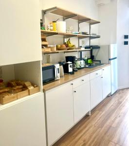 a kitchen with white cabinets and wooden floors at Lexie Suites in Rome