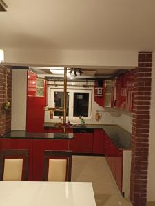 una cocina con armarios rojos y una mesa con sillas. en Domek na Odrzańskiej, en Moryń
