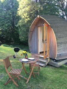 a small cabin with a table and two chairs and a grill at birdbox@glanrhyd in Pontardawe