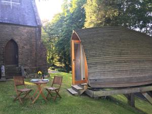 a small cabin with chairs and a table in a yard at birdbox@glanrhyd in Pontardawe
