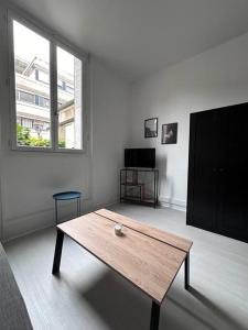 uma sala de estar com uma mesa de madeira e uma janela em L’insolite em Auxerre