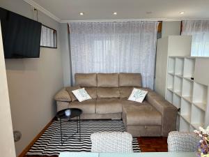 een woonkamer met een bank en een televisie bij Baiona-Mar, gastronomía y cultura in Baiona