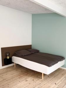 uma cama num quarto com uma parede branca em Charmerende bolig nær Domkirken em Ribe