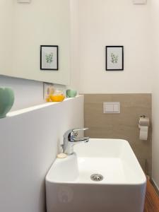 a white sink in a bathroom with two pictures on the wall at Golubina 3 - Soba sa Sopstvenim Kupatilom in Golubac