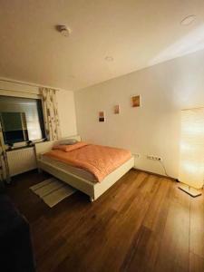 een slaapkamer met een bed en een houten vloer bij Wunderschöne Wohnung nähe Essen / Düsseldorf in Heiligenhaus