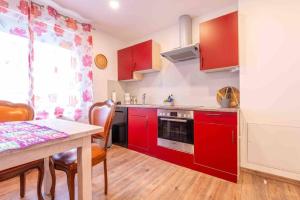 a kitchen with red cabinets and a table with chairs at Wunderschöne Wohnung nähe Essen / Düsseldorf in Heiligenhaus