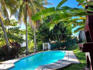a swimming pool with palm trees next to a house at Casa en Condominios San Blas 5 minutos del Tunco in La Libertad