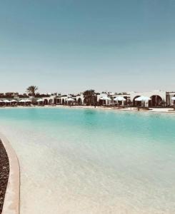 a large swimming pool with blue water and umbrellas at Le Sidi Cabana ( hacienda bay ) in El Alamein