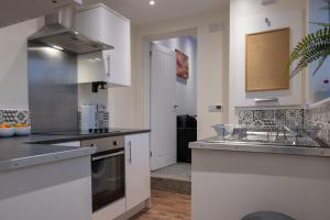 a kitchen with white cabinets and a sink at The Orange County in Stoke on Trent